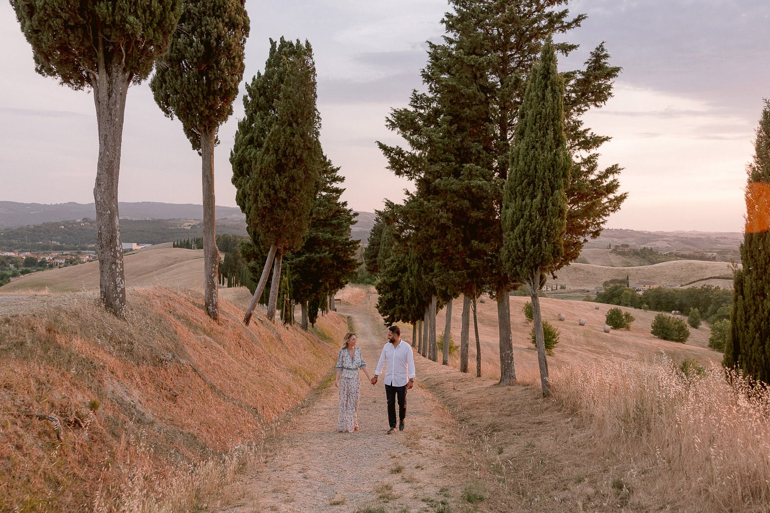 a couple walks in the fields of tuscany for the engagement session