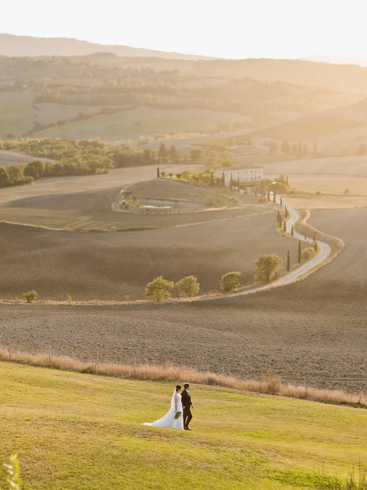 bride and groom stroll in the fields of tuscany after the elopement