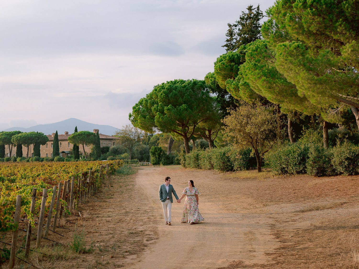 a couple walks in the fields around l'andana during their photo shoot